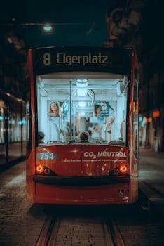 Red tram at night on tracks at Eigerplatz, Bern, Switzerland. Urban transit scene.