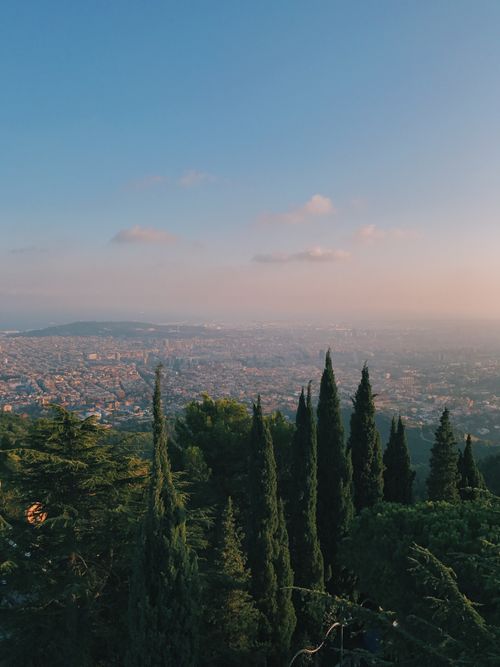 Free Stunning aerial view of Barcelona with lush greenery and a warm sunset glow. Stock Photo