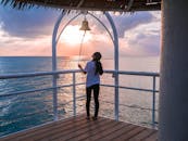 日落时分，一名女子站在海边甲板上敲响了钟