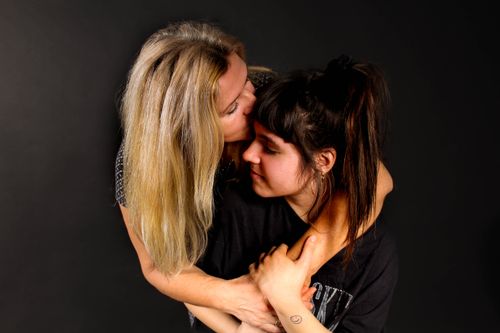 Free Two women sharing a heartfelt embrace, embodying affection and warmth against a dark background. Stock Photo
