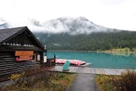 迷雾森林中，一个宁静的山湖旁有一座小木屋和独木舟