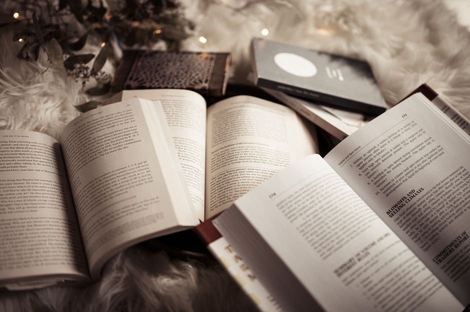 Open books placed on a soft, fluffy rug, surrounded by warm, ambient lighting for a cozy reading atmosphere.