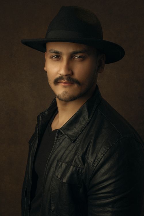 Free Portrait of a man with a fedora and leather jacket in warm lighting. Stock Photo