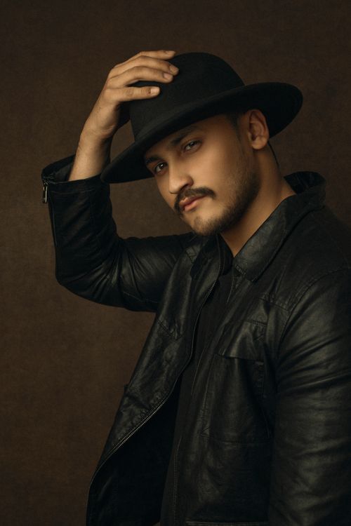 Free Studio portrait of a man wearing a black leather jacket and hat against a brown backdrop. Stock Photo