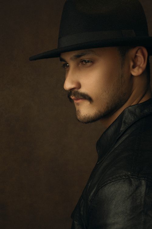 Free Portrait of a man wearing a leather jacket and fedora hat with a dark background. Stock Photo