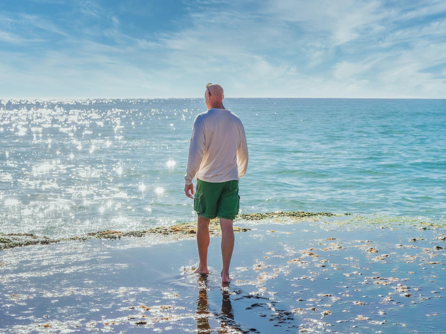Man in White Shirt and Green Shorts Standing on Seashore · Free Stock Photo