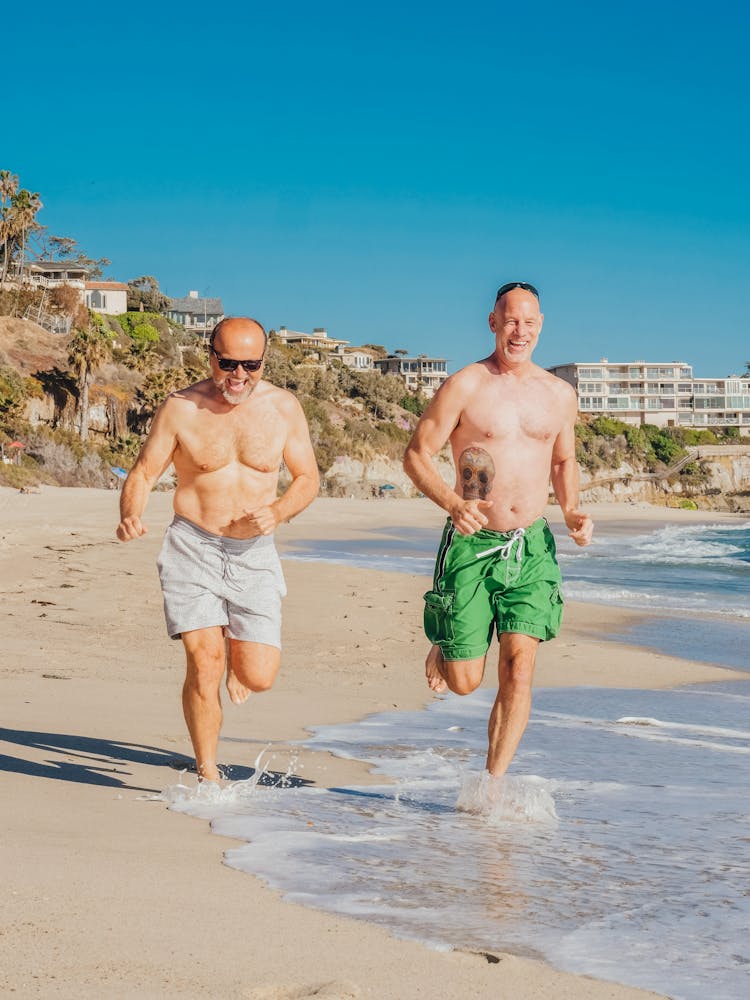 Two Men Running Together On A Beach 