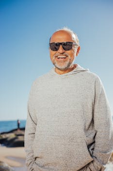 Happy senior man with sunglasses smiling on a sunny beach. Perfect for lifestyle and travel themes.