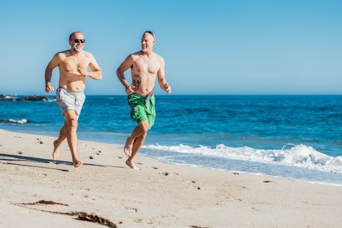 Free Man in Green and Blue Shorts Running on Beach Stock Photo