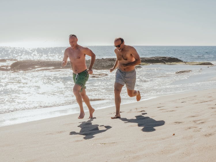 Two Men Running Together On A Beach 