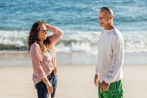 Man in White Long Sleeve Shirt with Woman at the Beach