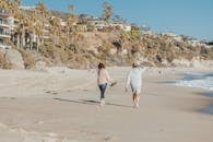 成熟的夫妇沿着阳光明媚的海滩散步，享受海风和风景