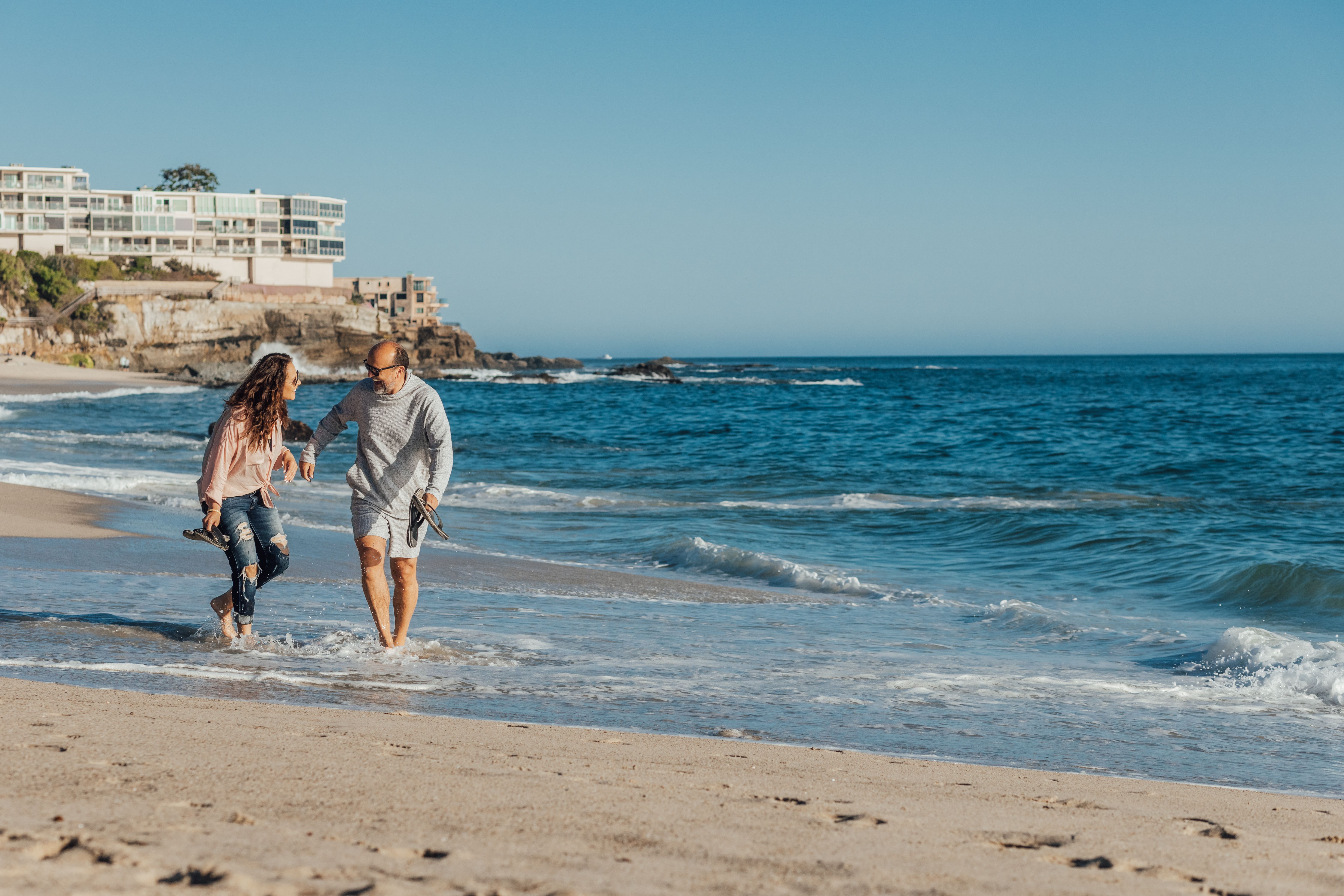 A couple strolls along a scenic beach, enjoying a sunny summer day by the ocean.