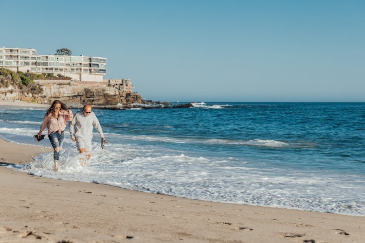 A Man And A Woman Walking On The Shore 