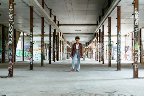 Woman in Red Leather Jacket Standing with Skateboard in an Abandoned Building  