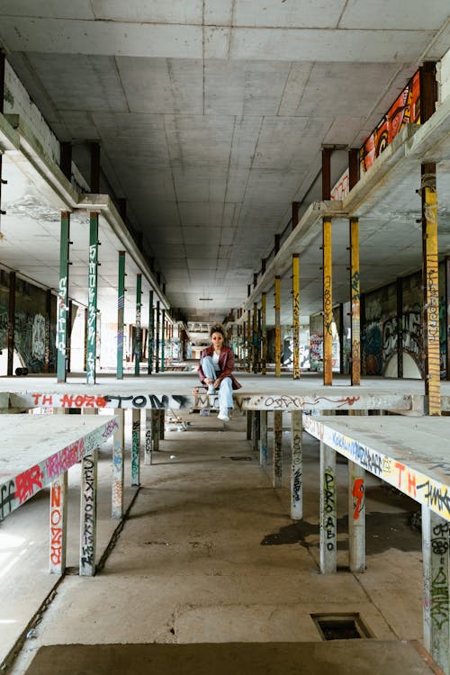 Young Woman Sitting on a Concrete Platform in an Abandoned Building