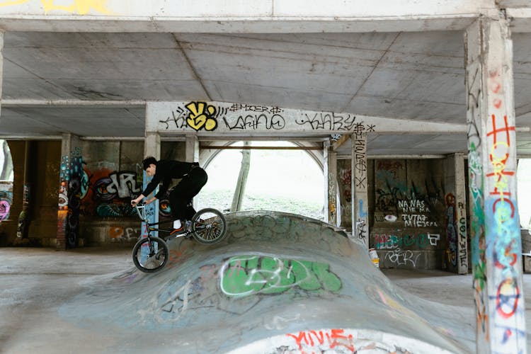 Young Man In Black Long Sleeve Shirt Riding On Bicycle On A Ramp