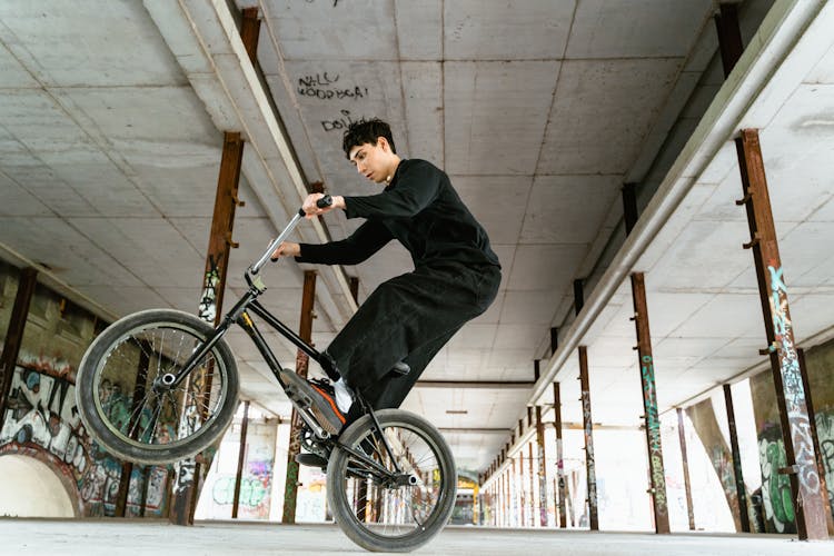 Young Man In Black Long Sleeve Shirt Doing Trick Work Riding On Bicycle 