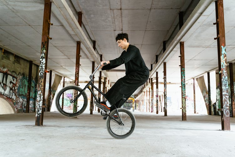 Young Man In Black Long Sleeve Shirt Doing Trick Work Riding On Bicycle