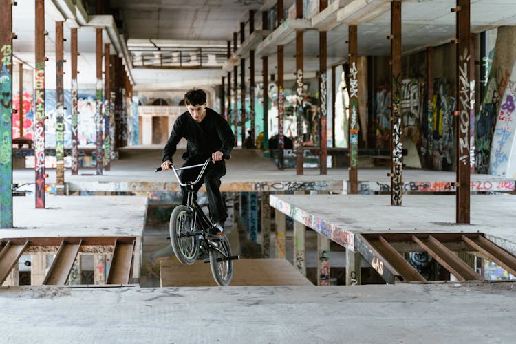 Young Man In Black Long Sleeve Shirt Doing Trick Work Riding On Bicycle