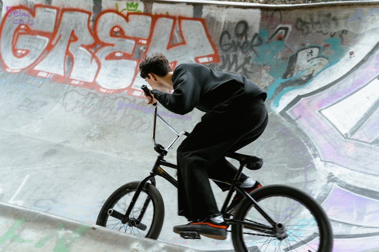 A Man In Black Sweater Riding A Bicycle