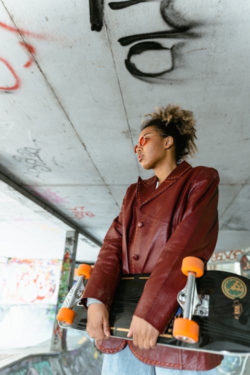 A Woman in Red Leather Jacket Carrying a Skateboard