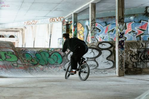 Free A BMX rider expertly performing tricks among graffiti-covered ramps in an urban skate park. Stock Photo