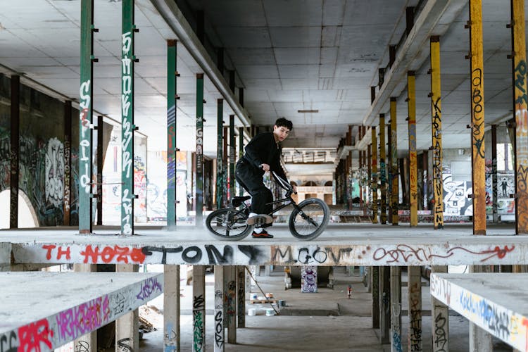 A Man In Black Sweater Riding A Bike