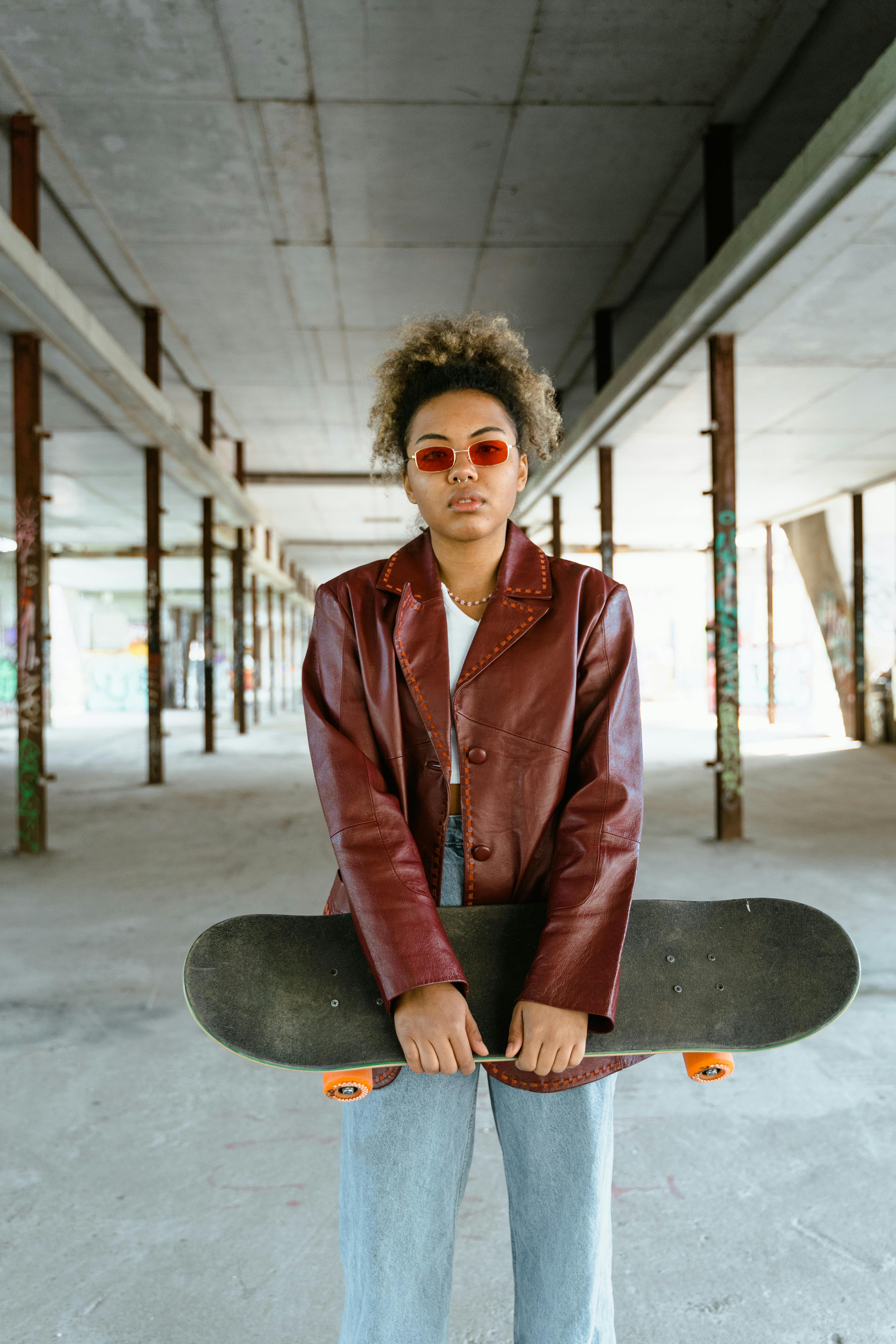 woman in red blazer holding black skateboard