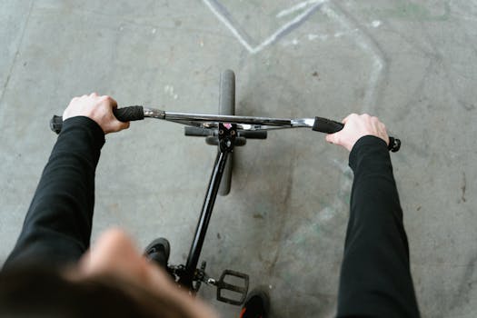 Top-down view of an individual gripping a bicycle's handlebars on an urban pavement.