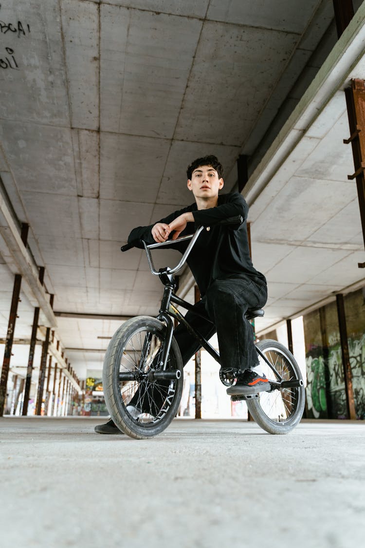 A Man In Black Sweater Riding A Bike