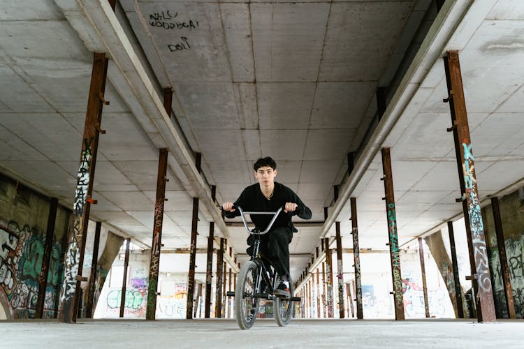 A Man In Black Sweater Riding A Bicycle