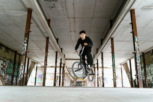 Man in Black Shirt Jumping a Bicycle