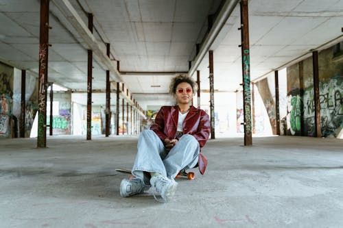 A Woman in a Red Leather Jacket Sitting on a Skateboard