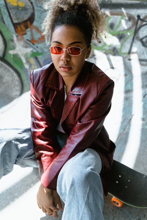 A Woman in a Red Leather Jacket Sitting on a Skateboard