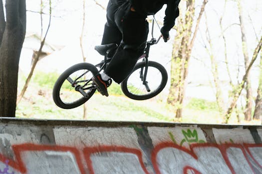 Energetic BMX rider performs a stunt at an outdoor skatepark with colorful graffiti.