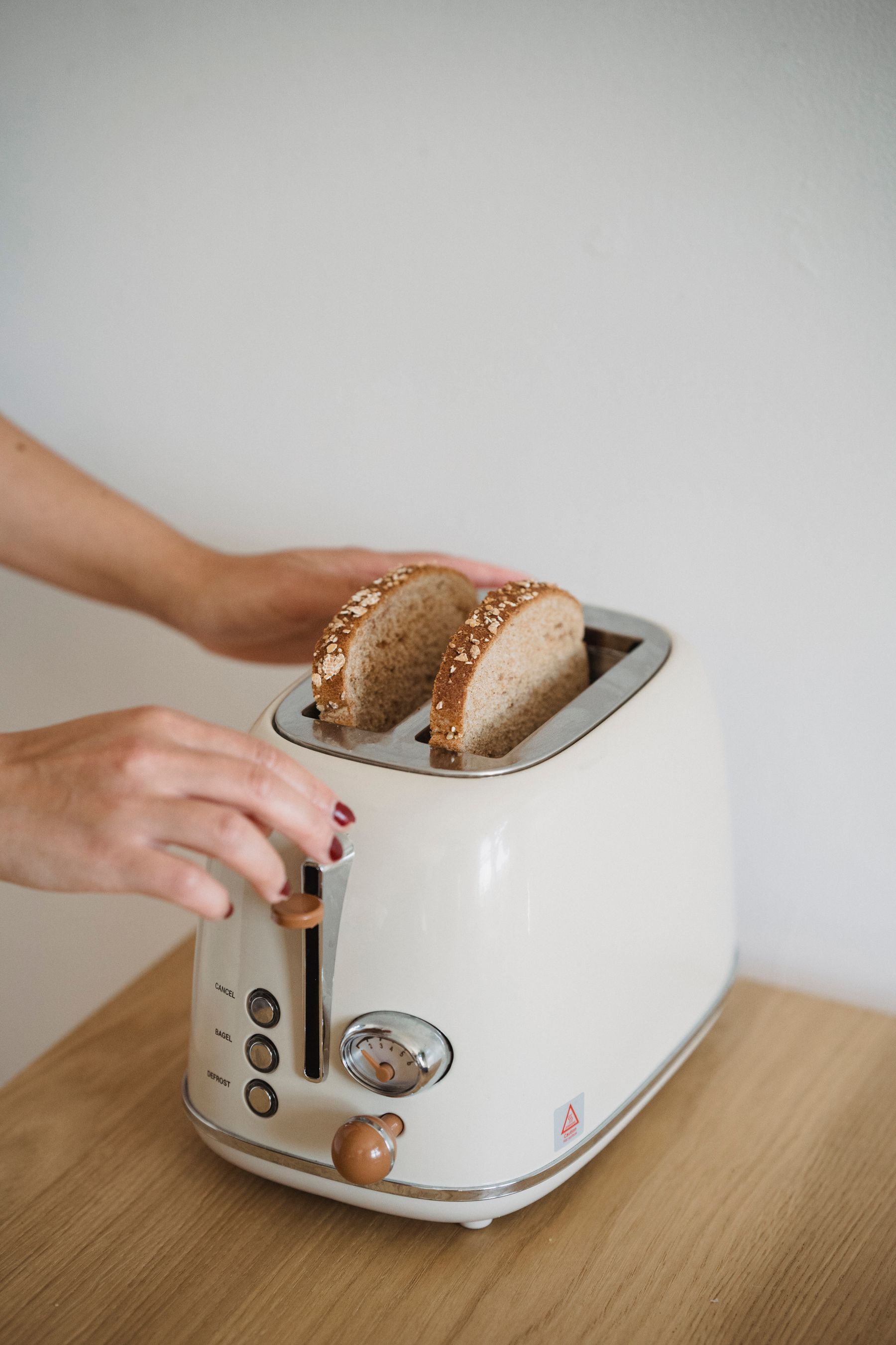 Person using a toaster to prepare breakfast in a bright kitchen