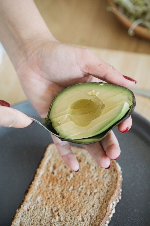 Free Close-up of a hand slicing fresh avocado for toast. Perfect for food blogs. Stock Photo