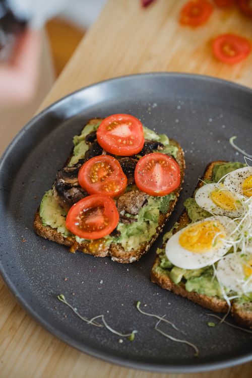 Free Delicious avocado toast topped with fresh tomatoes and boiled eggs, perfect for breakfast. Stock Photo