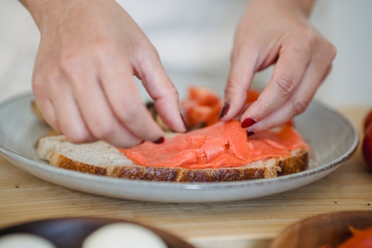 Close-up Of Woman Hands Making Salmon Sandwich