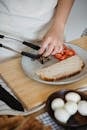 Person Arranging Food on a Plate With Bread and Sliced Tomatoes
