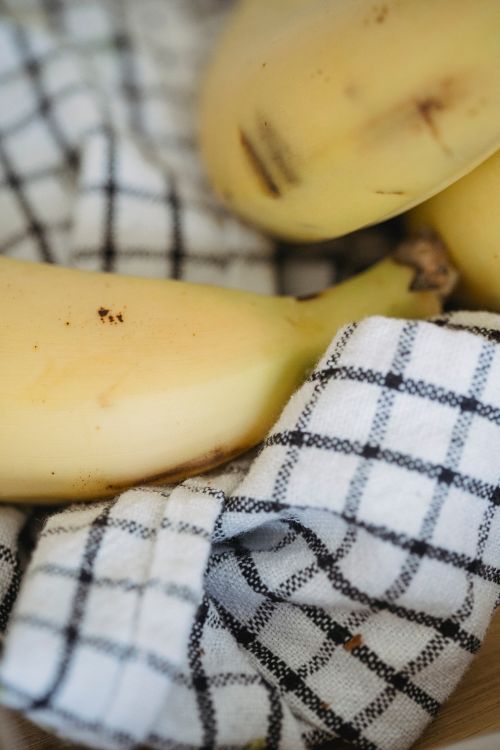 Free Close-up of ripe bananas on a black and white checkered cloth, showcasing freshness and simplicity. Stock Photo
