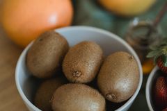 Close-up of fresh kiwi and citrus fruits in white bowls on a wooden table. Perfect for healthy eating themes.