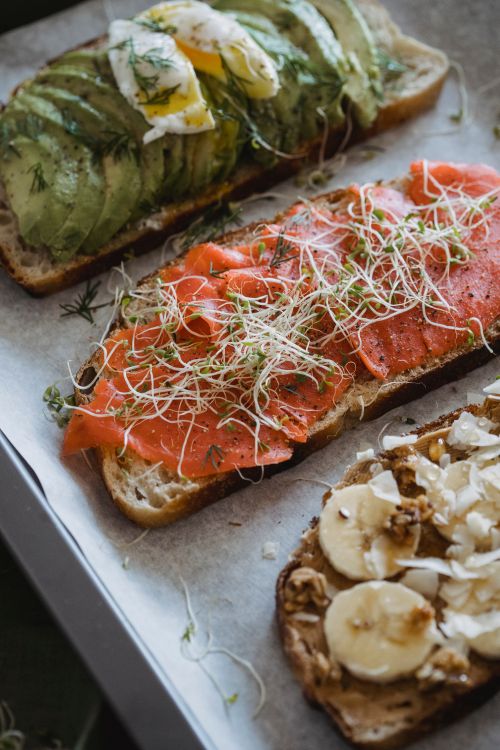 Free Mouthwatering open-faced sandwiches with avocado, salmon, and banana toppings. Stock Photo