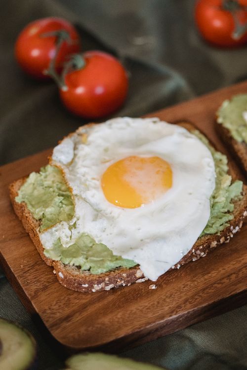 Free Close-up of avocado toast topped with a fried egg, perfect brunch meal. Stock Photo