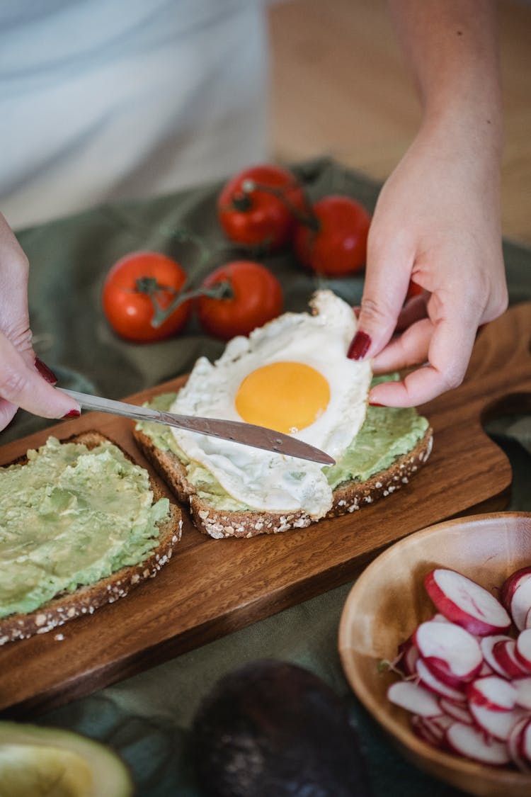 Woman Preparing Bread With Avocado And Fried Egg