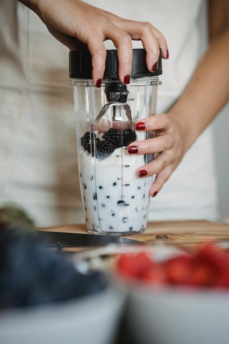 Close-up Of Woman Making Smoothie In Blender
