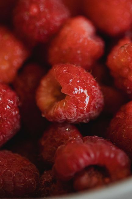 A close-up of fresh red raspberries with water droplets showcasing their vibrant color and juiciness.