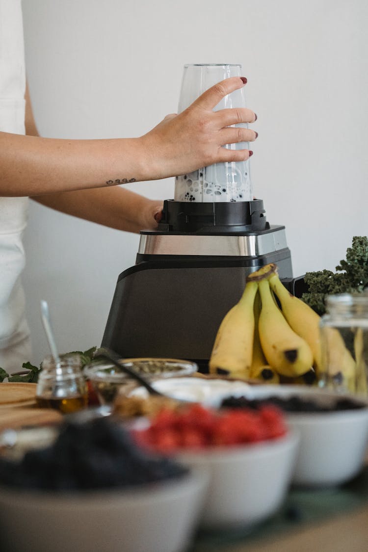 Woman Making A Shake With A Blender And Bowls With Fruits