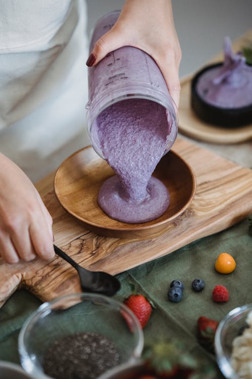Free A Person Putting Smoothie in a Wooden Bowl Stock Photo